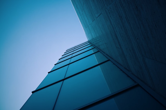 View from below of a modern blue mirrored building against a clear sky representing Smarte EPC challenges